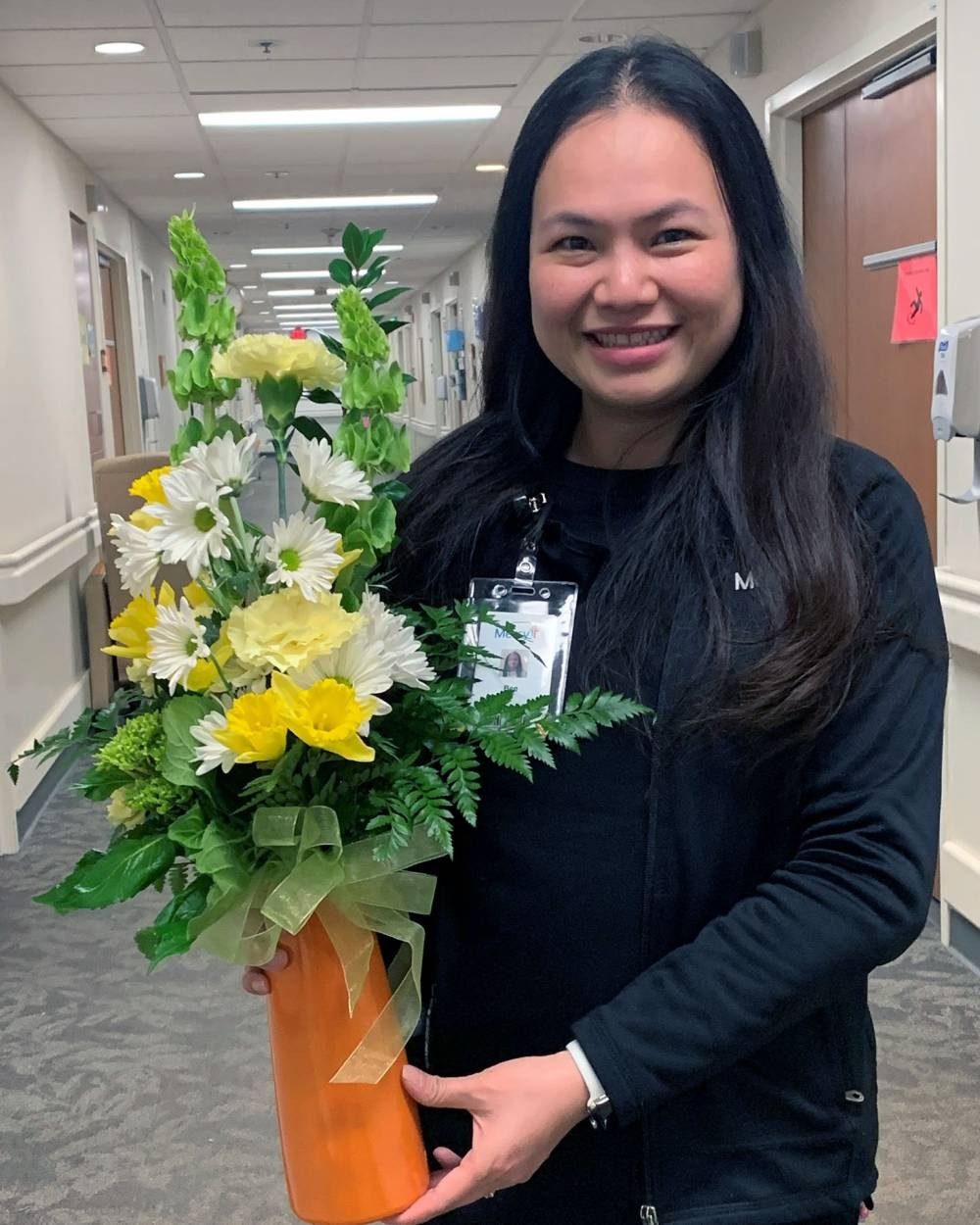 Bee Nguyen, Patient Care Associate, Orthopedics, poses with the flowers presented to her for winning the Daffodil Award.