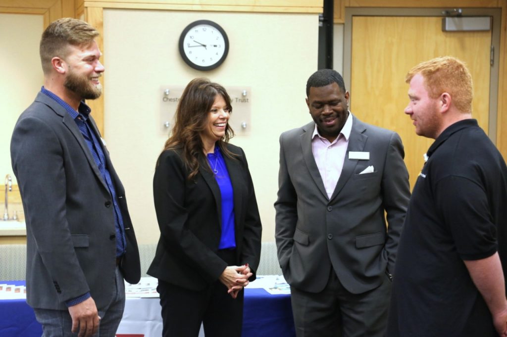 Four people wearing business attire and standing in a conference room