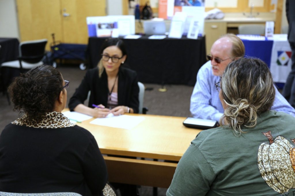 Four people wearing business attire and sitting around a conference table