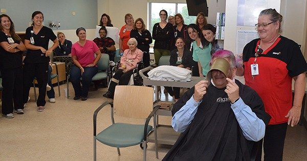 Therapy Services Director Eric Baldonado gets his hair colored bright pink by nurse Karen Brewer.